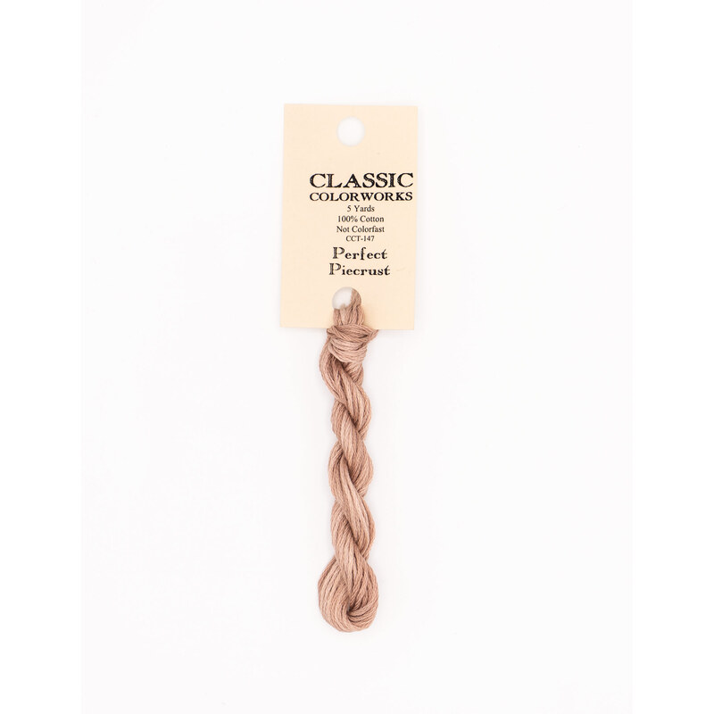 A skein of tan embroidery floss, twisted and bundled, with a cream and black label featuring the brand name and color information.
