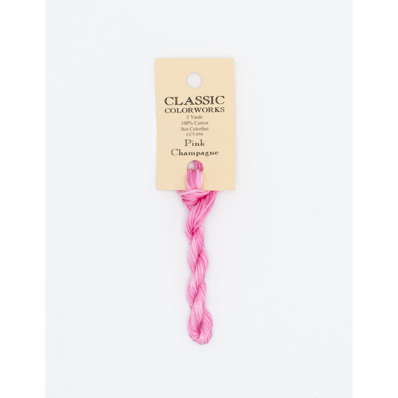 A skein of bright pink embroidery floss, twisted and bundled, with a cream and black label featuring the brand name and color information.
