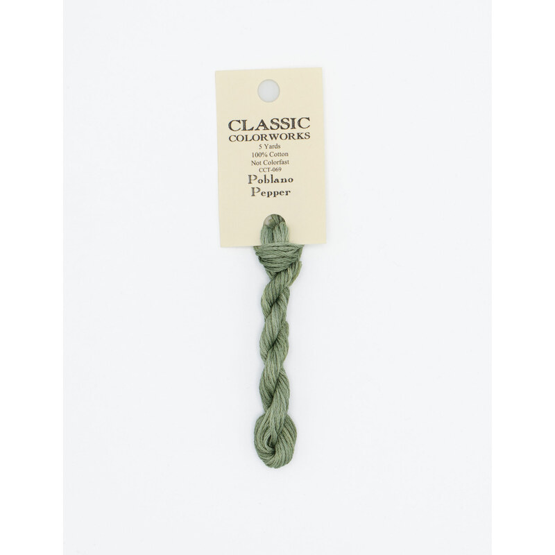 A skein of green embroidery floss, twisted and bundled, with a cream and black label featuring the brand name and color information.