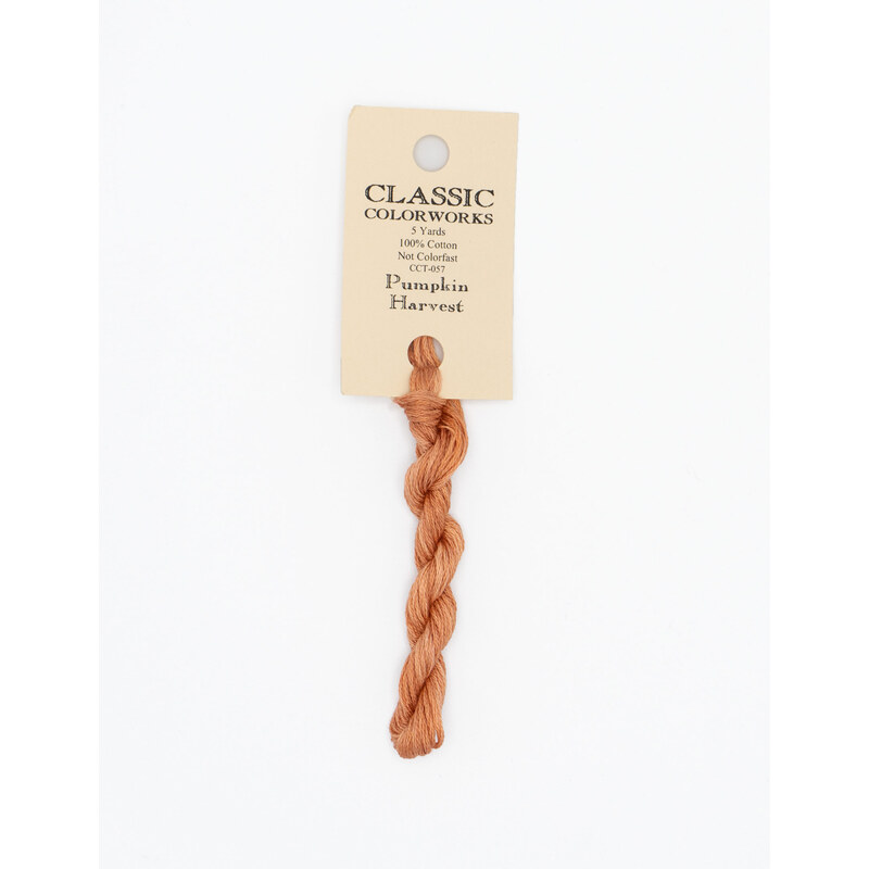 A skein of light pumpkin embroidery floss, twisted and bundled, with a cream and black label featuring the brand name and color information.