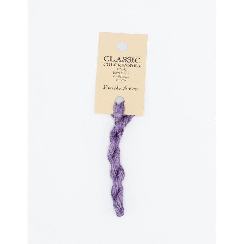 A skein of lavender embroidery floss, twisted and bundled, with a cream and black label featuring the brand name and color information.