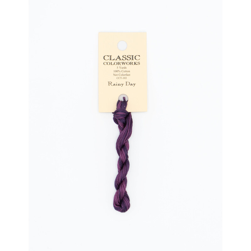 A skein of dark plum embroidery floss, twisted and bundled, with a cream and black label featuring the brand name and color information.