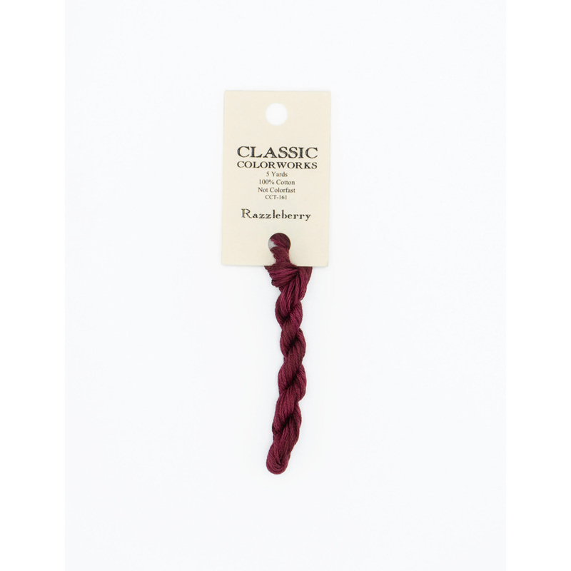 A skein of burgundy embroidery floss, twisted and bundled, with a cream and black label featuring the brand name and color information.