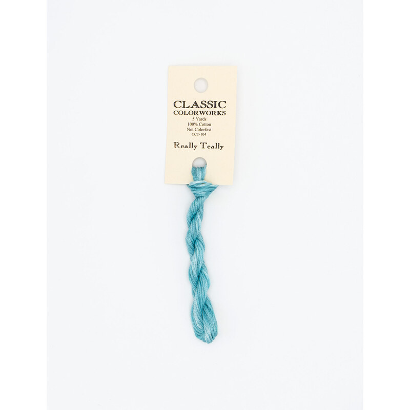 A skein of teal embroidery floss, twisted and bundled, with a cream and black label featuring the brand name and color information.