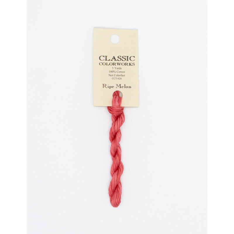 A skein of bright pink embroidery floss, twisted and bundled, with a cream and black label featuring the brand name and color information.