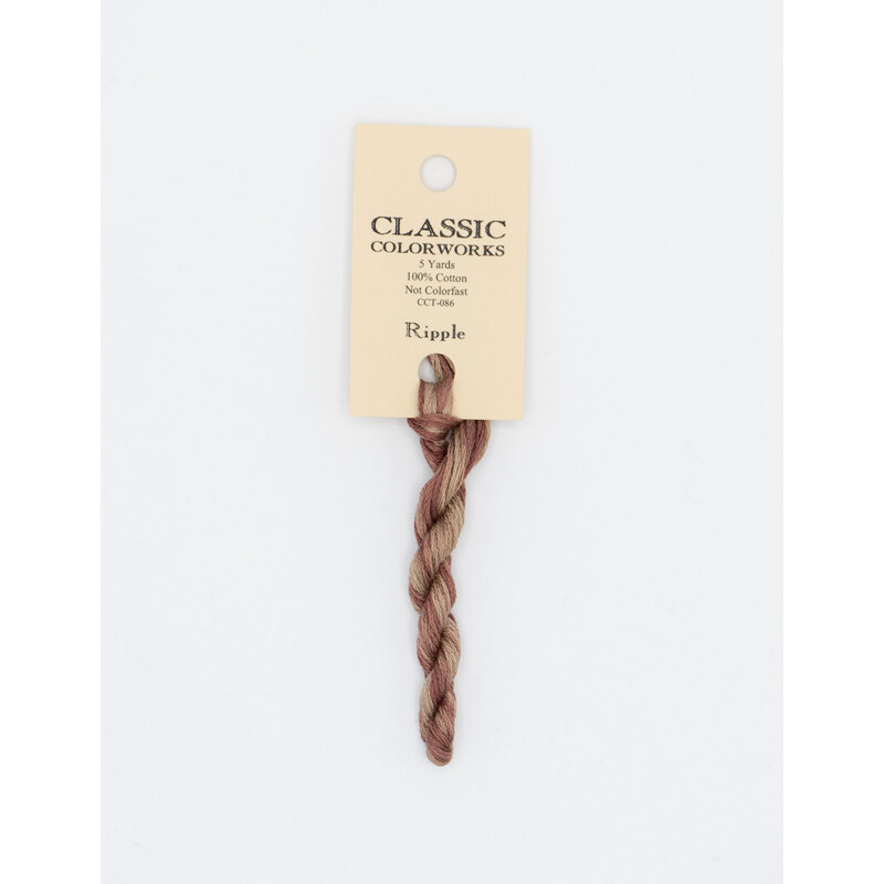 A skein of variegated terra cotta and tan embroidery floss, twisted and bundled, with a cream and black label featuring the brand name and color information.