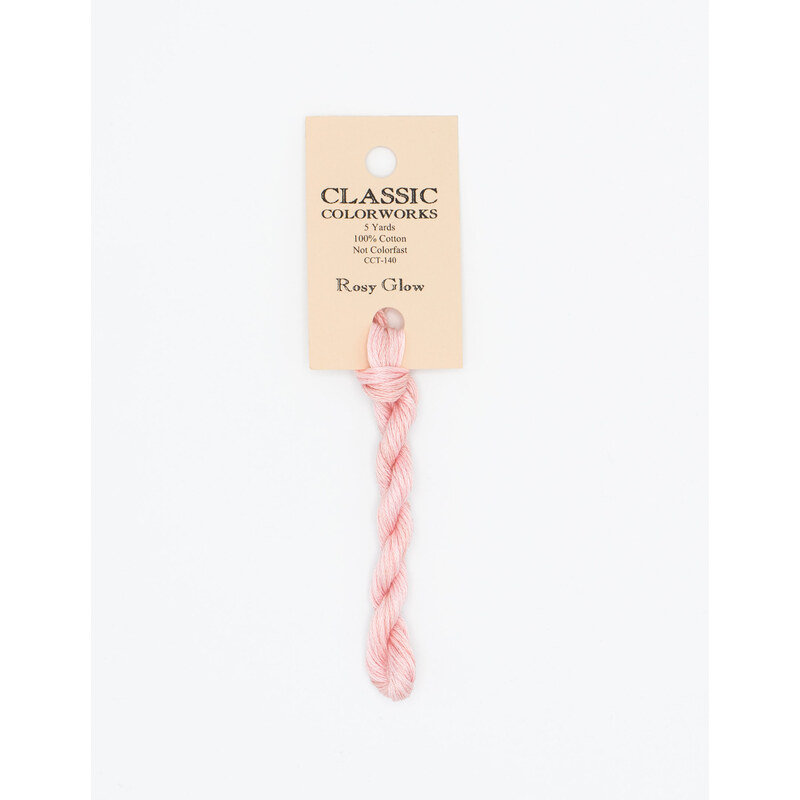 A skein of pastel pink embroidery floss, twisted and bundled, with a cream and black label featuring the brand name and color information.