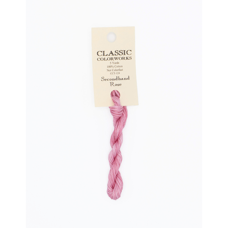 A skein of pink embroidery floss, twisted and bundled, with a cream and black label featuring the brand name and color information.