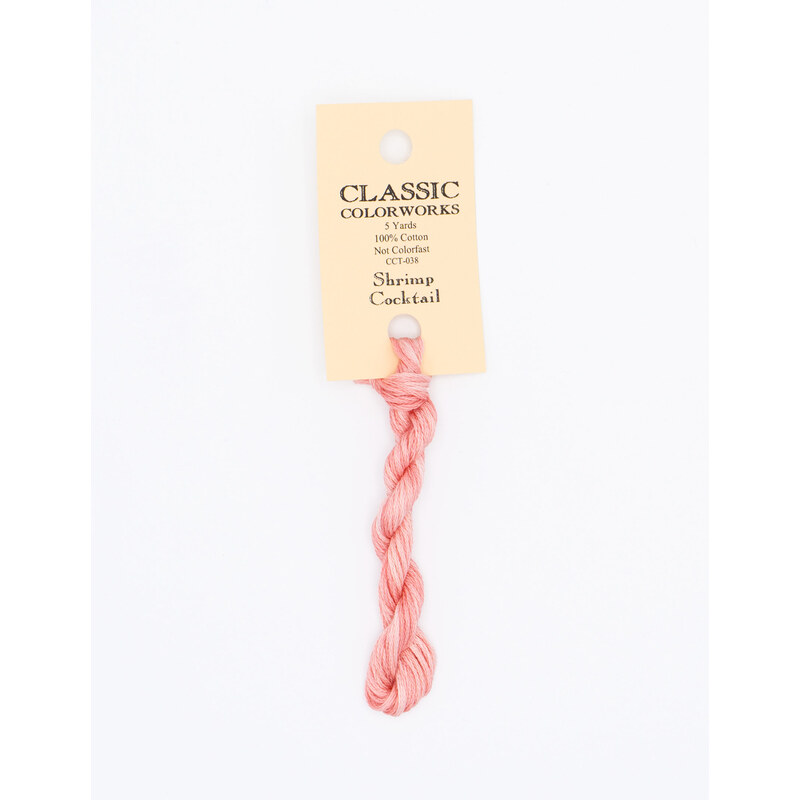 A skein of pink embroidery floss, twisted and bundled, with a cream and black label featuring the brand name and color information.