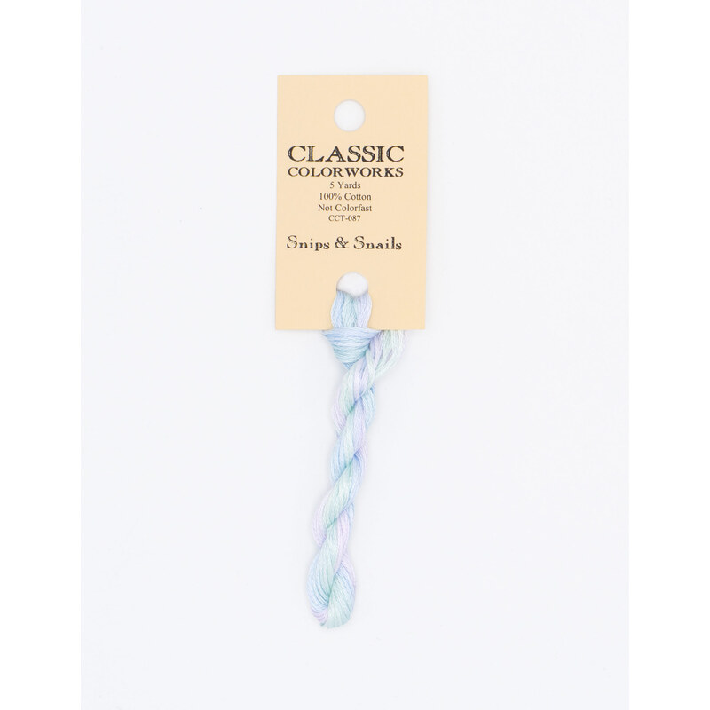 A skein of variegated pastel blue, green, and purple embroidery floss, twisted and bundled, with a cream and black label featuring the brand name and color information.