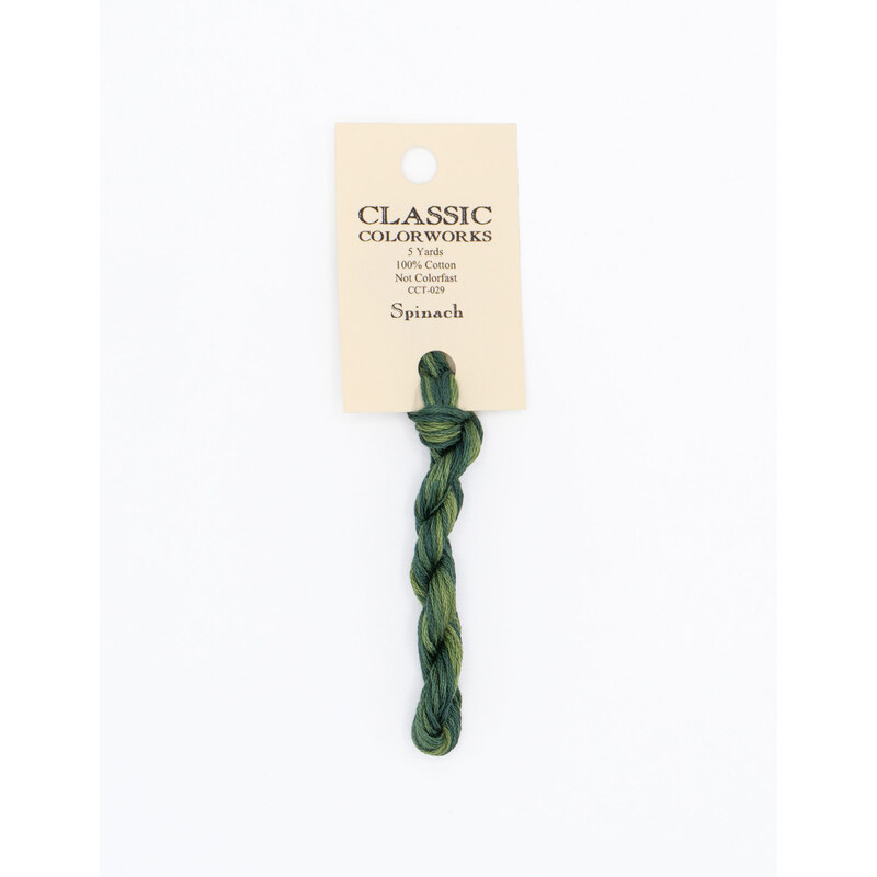 A skein of dark green embroidery floss, twisted and bundled, with a cream and black label featuring the brand name and color information.