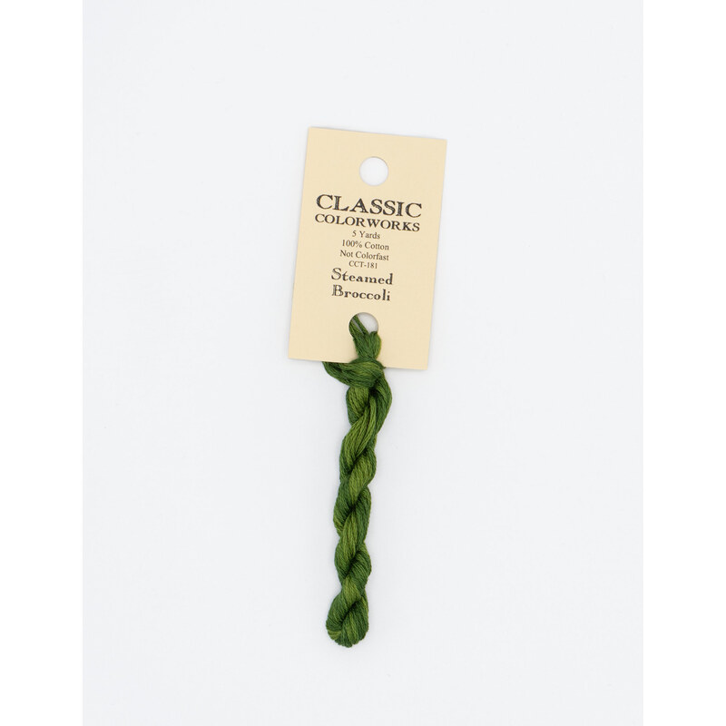 A skein of green embroidery floss, twisted and bundled, with a cream and black label featuring the brand name and color information.