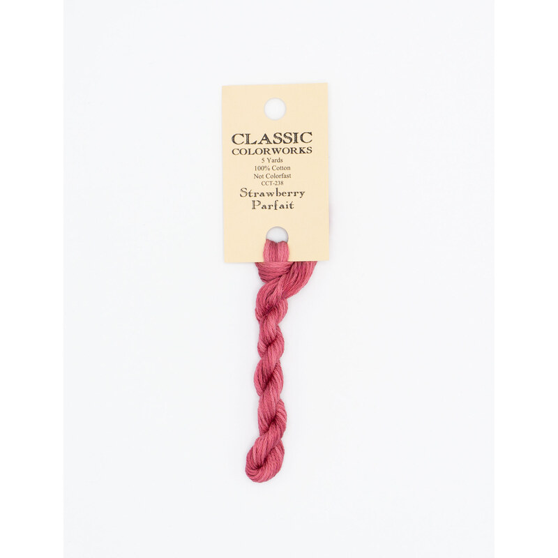 A skein of hot pink embroidery floss, twisted and bundled, with a cream and black label featuring the brand name and color information.