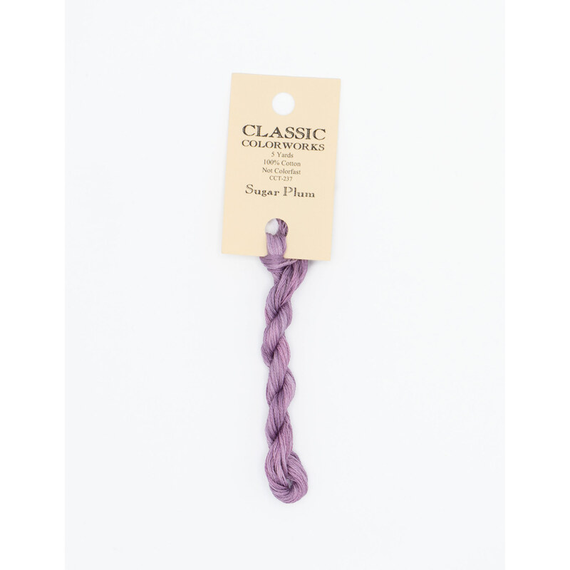 A skein of light violet embroidery floss, twisted and bundled, with a cream and black label featuring the brand name and color information.