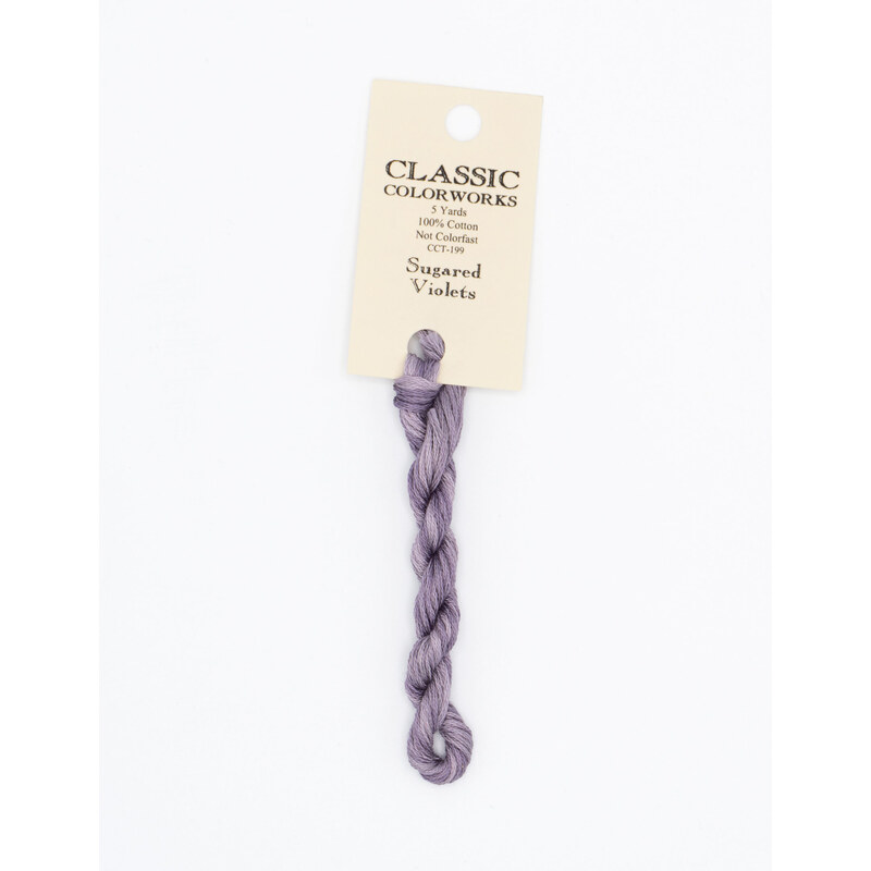 A skein of muted purple embroidery floss, twisted and bundled, with a cream and black label featuring the brand name and color information.