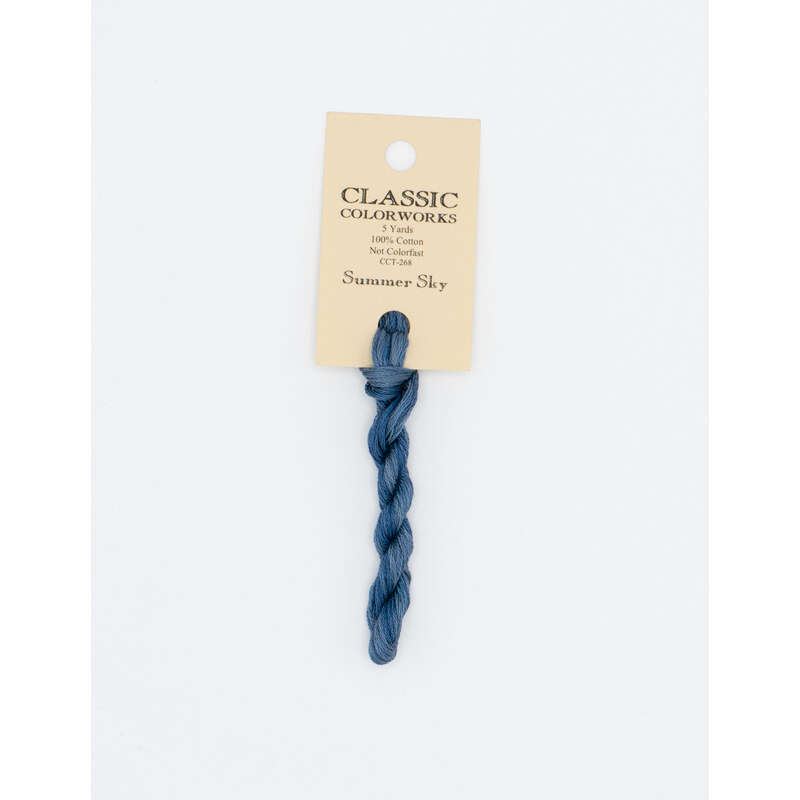 A skein of deep blue embroidery floss, twisted and bundled, with a cream and black label featuring the brand name and color information.