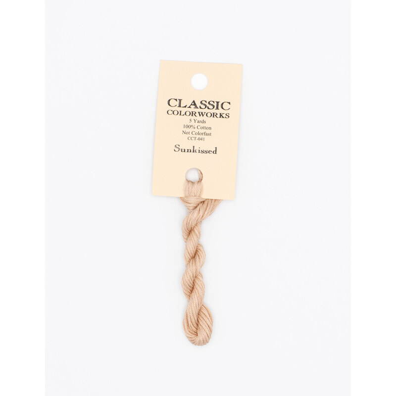 A skein of pale orange embroidery floss, twisted and bundled, with a cream and black label featuring the brand name and color information.