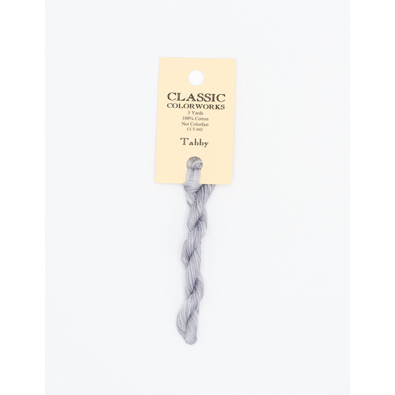 A skein of gray embroidery floss, twisted and bundled, with a cream and black label featuring the brand name and color information.