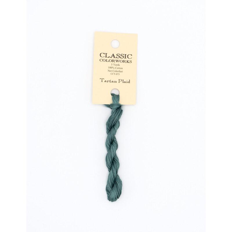 A skein of dark teal embroidery floss, twisted and bundled, with a cream and black label featuring the brand name and color information.