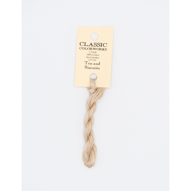 A skein of cream embroidery floss, twisted and bundled, with a cream and black label featuring the brand name and color information.