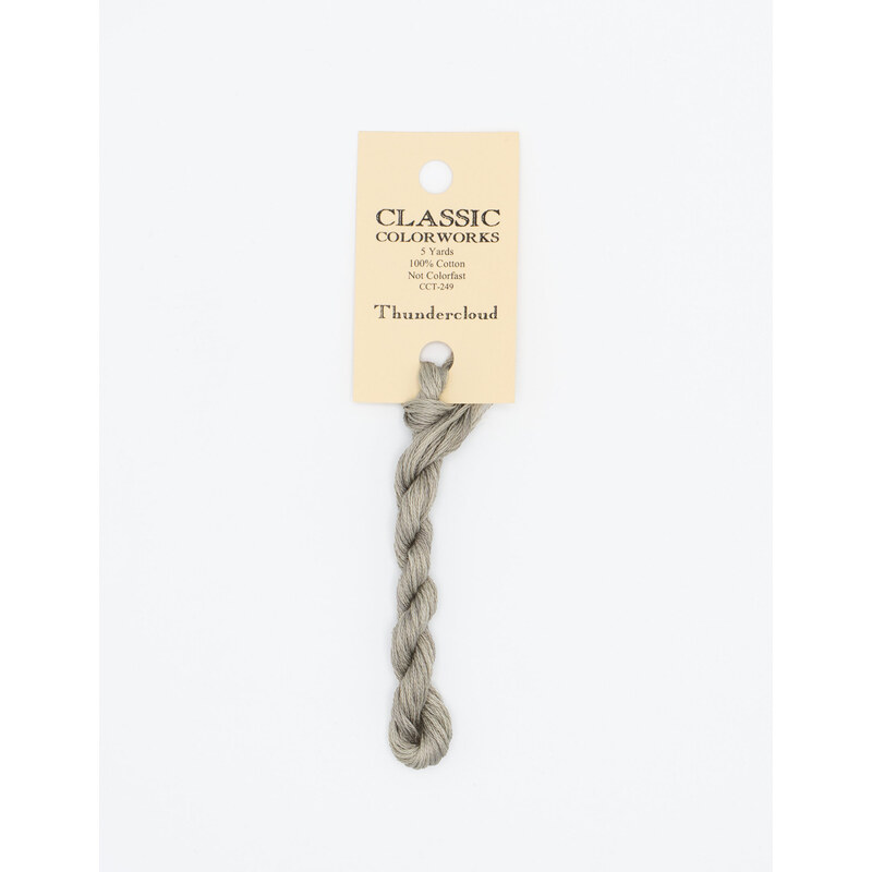 A skein of gray embroidery floss, twisted and bundled, with a cream and black label featuring the brand name and color information.