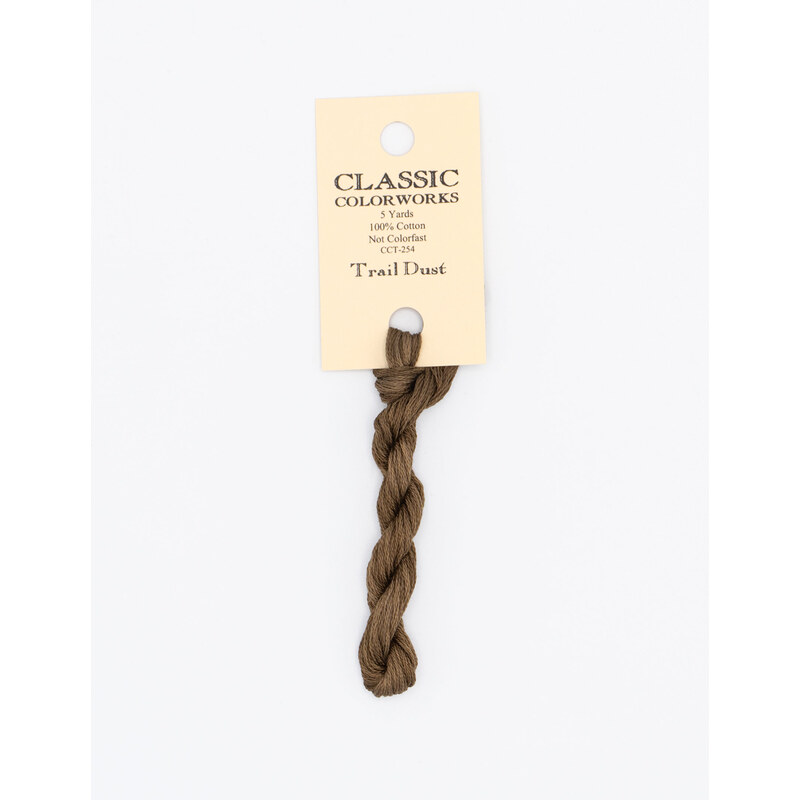 A skein of brown embroidery floss, twisted and bundled, with a cream and black label featuring the brand name and color information.