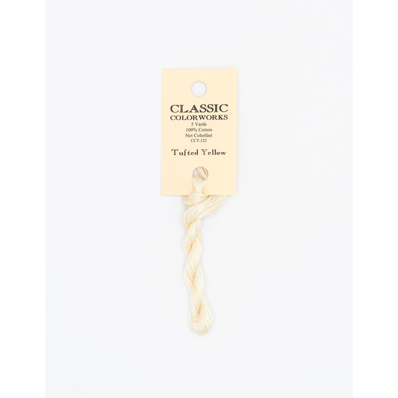 A skein of very light yellow embroidery floss, twisted and bundled, with a cream and black label featuring the brand name and color information.