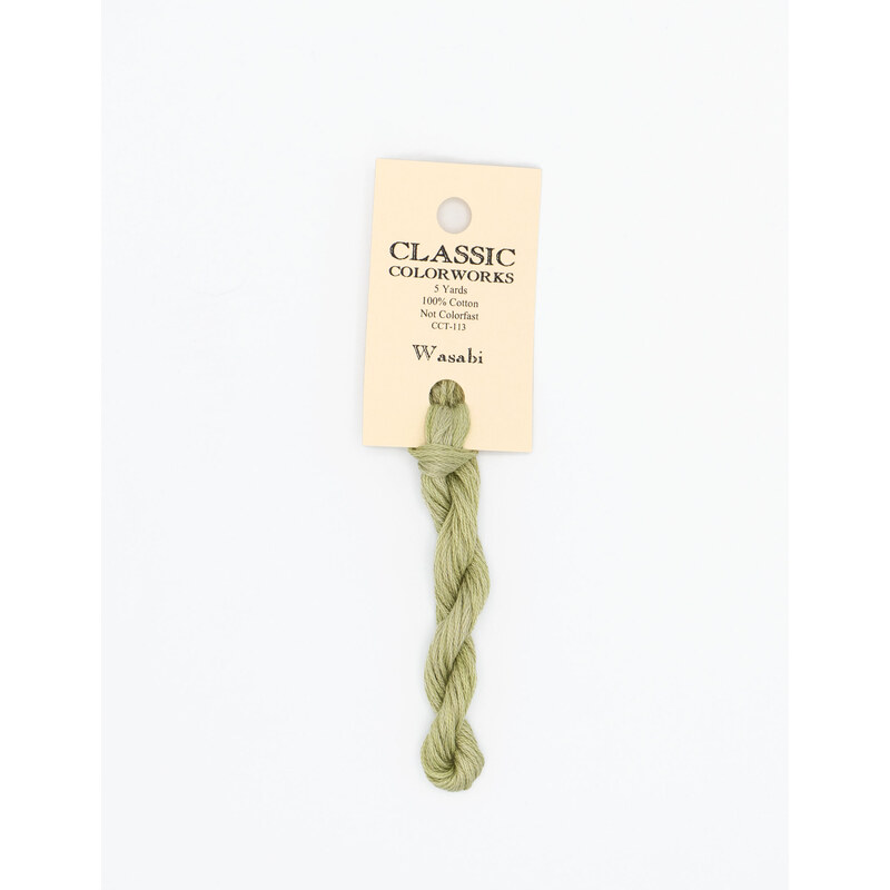 A skein of pastel green embroidery floss, twisted and bundled, with a cream and black label featuring the brand name and color information.