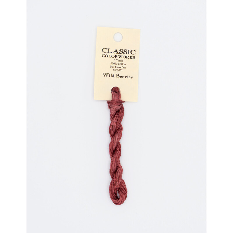 A skein of raspberry red embroidery floss, twisted and bundled, with a cream and black label featuring the brand name and color information.
