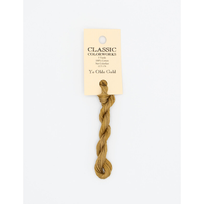 A skein of gold embroidery floss, twisted and bundled, with a cream and black label featuring the brand name and color information.