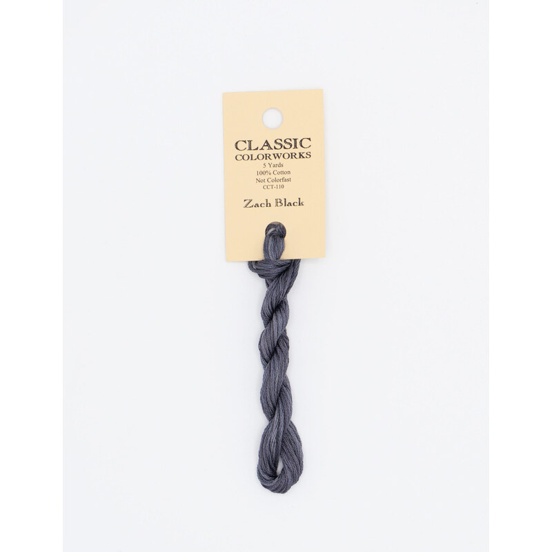 A skein of blue gray embroidery floss, twisted and bundled, with a cream and black label featuring the brand name and color information.