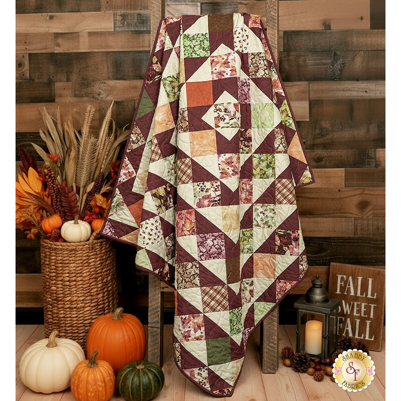 A shot of the quilt artfully draped over a wooden ladder to show drape and form, staged with coordinating autumnal décor.