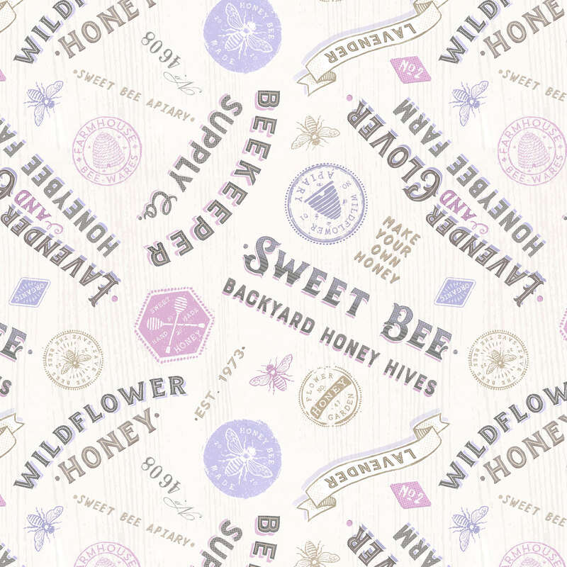 textured white fabric featuring vintage lettered signs and stamps in lilac, lavender, tan, and black.