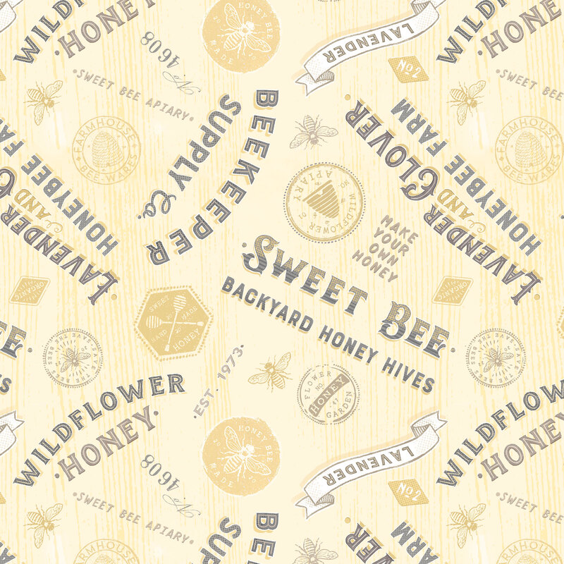 textured yellow fabric featuring vintage lettered signs in black text, yellow stamps, and yellow bees.