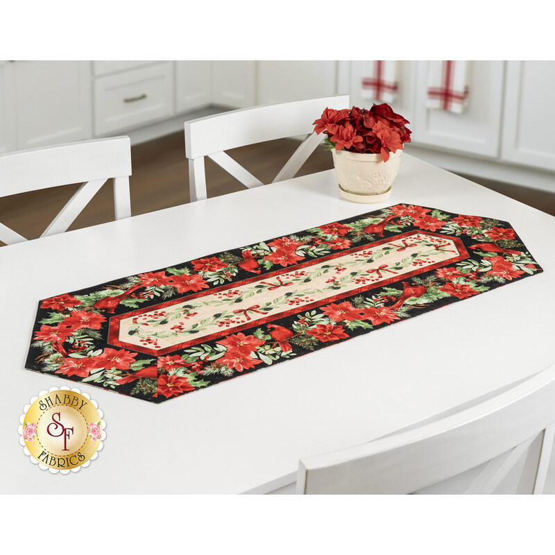The completed Easy Striped Table Runner colored in floral red, cream, and black fabrics from the Cardinal Celebration collection by Timeless Treasures Fabrics, staged on a white table.