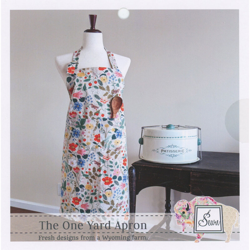 Floral-patterned apron displayed on a mannequin beside a vintage canister, showcasing farm-inspired design.