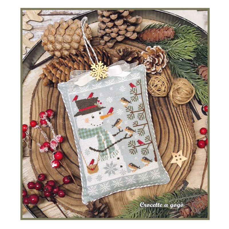 The completed project, a snowman surrounded by birds and snowflakes, staged with coordinating holiday decor.