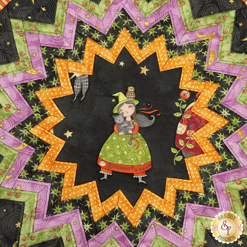 A super close up top-down shot of the folded star center, showcasing the black fabric with a witch and her cat.