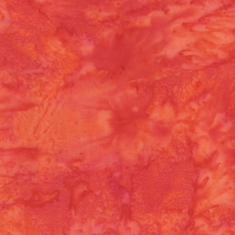 A mottled red, orange, and pink watercolor batik fabric.