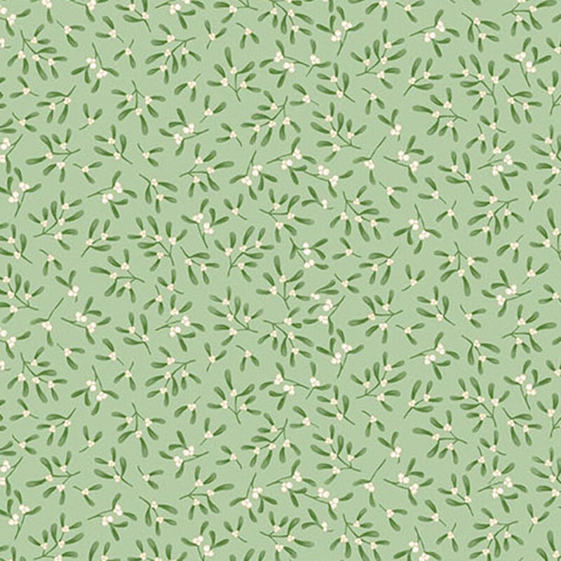 Sprigs of mistletoe tossed on pastel green fabric.