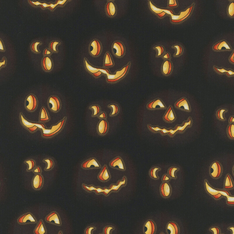 Illuminated jack-o'-lantern faces carved into black fabric.
