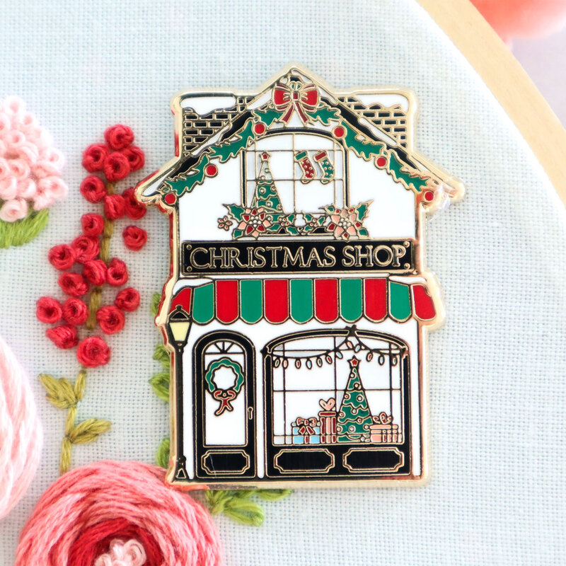 A vintage store shaped magnetic needle minder displayed on a hand embroidery project 