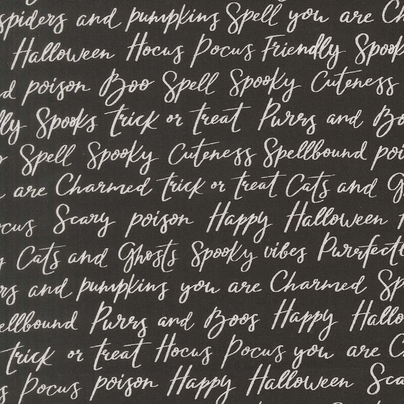 Black fabric with rows of Halloween-themed words and phrases in cursive script.