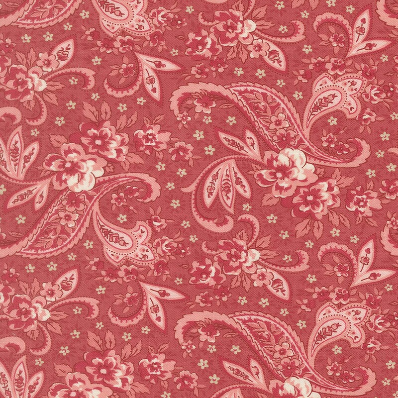 A salmon pink fabric with a light and dark pink floral paisley design with small sage green flowers