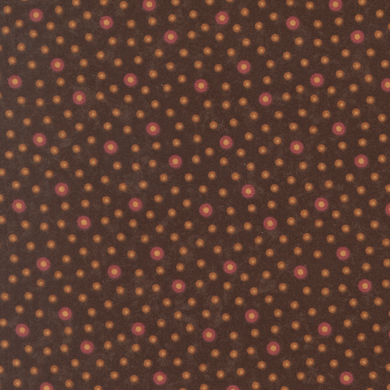 Flannel fabric featuring red and orange rings with tan centers tossed on a dark earth brown background.