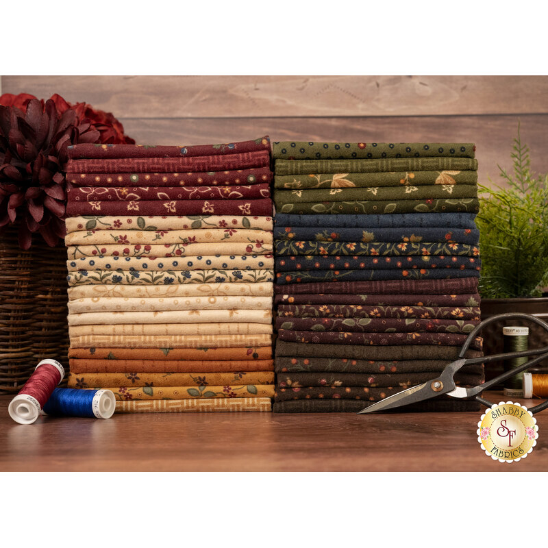 Two stacks of the flannel fabrics included in the Flannel Season collection, with flowers and a plant and thread and baskets and scissors.