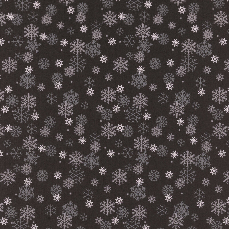White and gray snowflakes tossed on a soft black background.