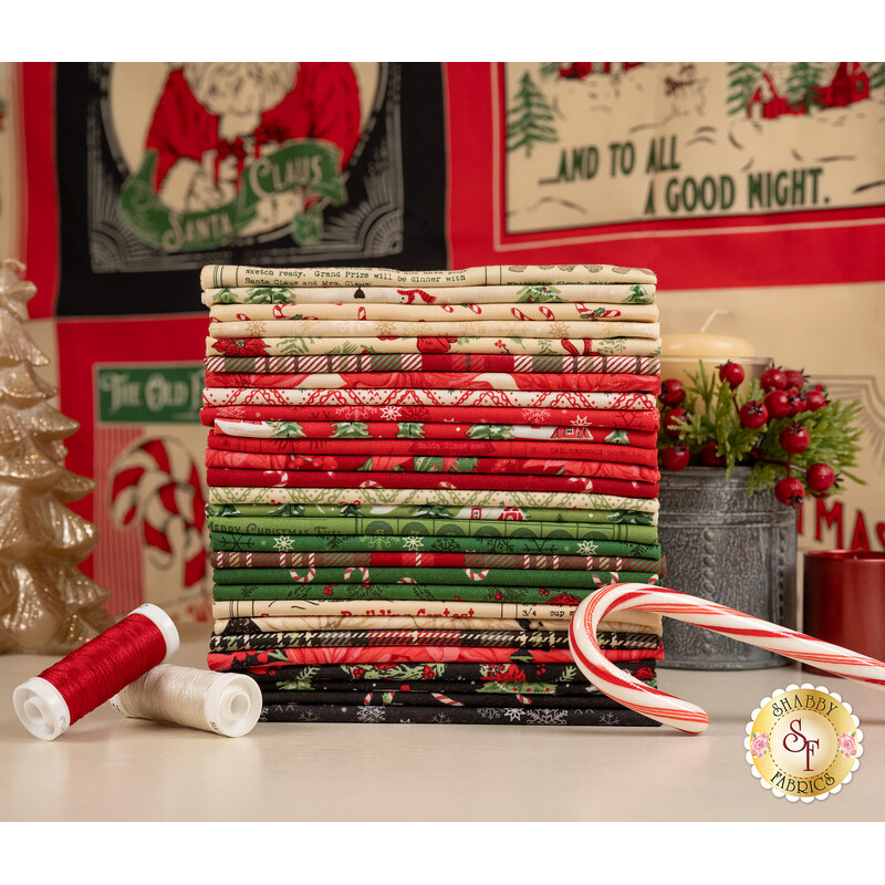A stack of fabrics included in the Holiday Cheer collection, with a panel, and a tree and a candle and thread and a candy cane.