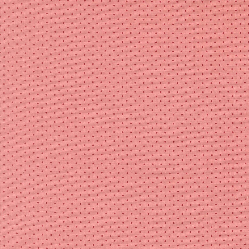 Salmon pink fabric with a delicate pattern of red pin dots