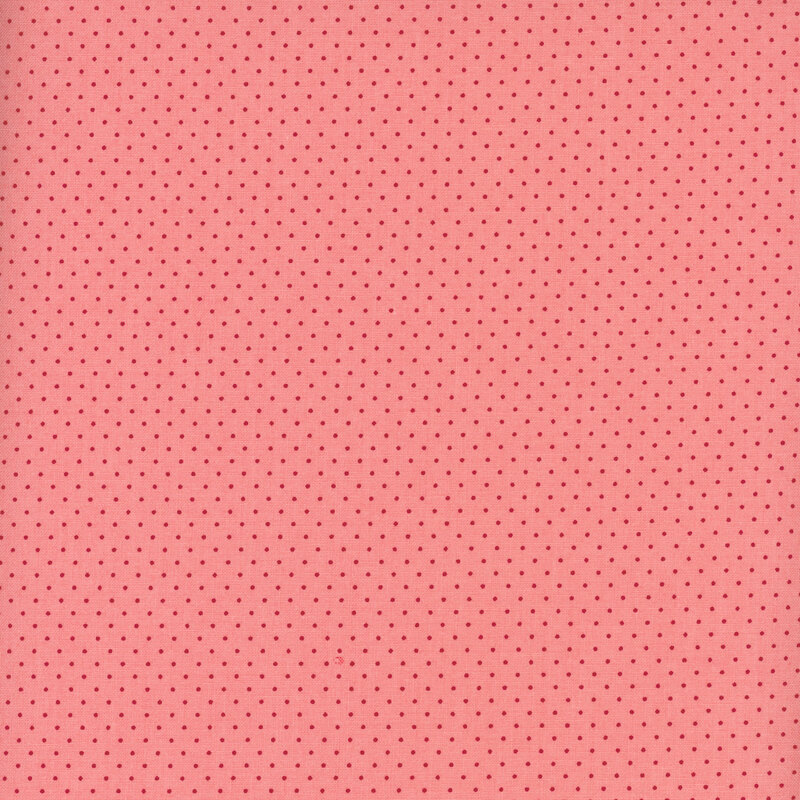 Salmon pink fabric with a delicate pattern of red pin dots